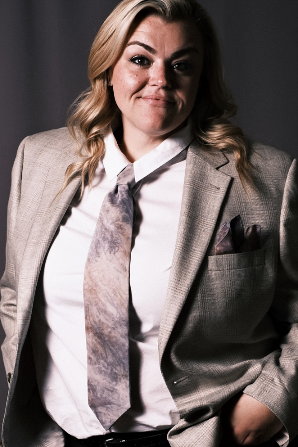 woman with a beige blazer and grey necktie