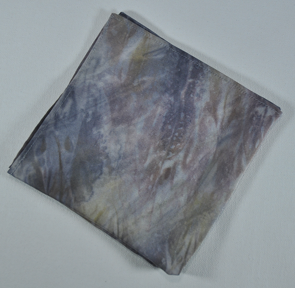 piece of gray fabric with brown, black and amber highlights folded into a square